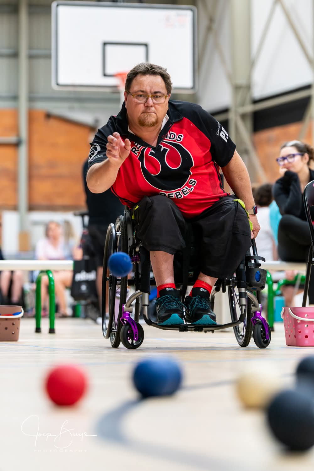 A Rebels player mid-throw with boccia balls in the foreground